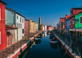 Vibrant houses and canal in Burano, Italy, showcasing vivid reflections and boats.