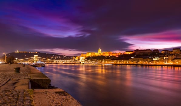 Scenic night view of Budapest's Chain Bridge and Danube River reflecting city lights.